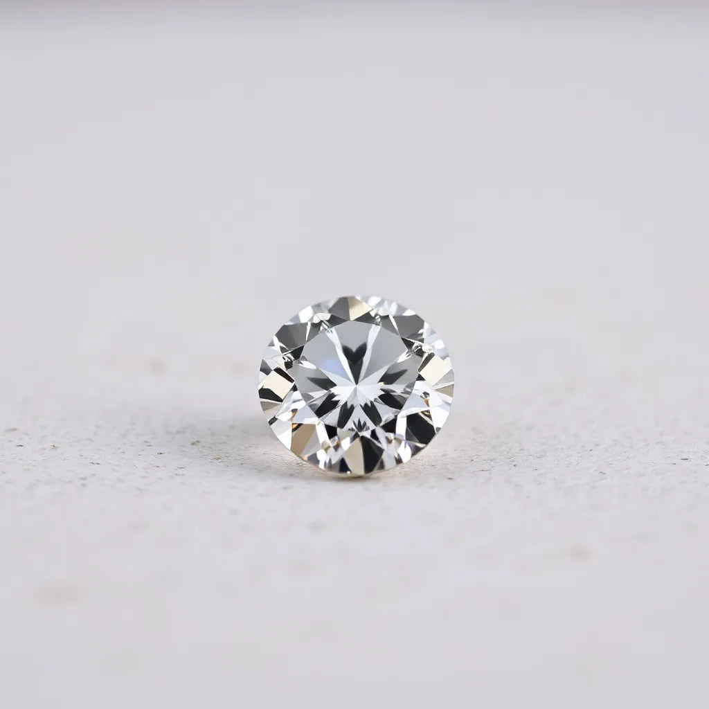 A sharply faceted diamond gem with bright reflections on a neutral background