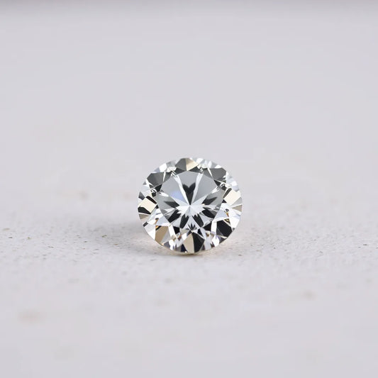 A sharply faceted diamond gem with bright reflections on a neutral background