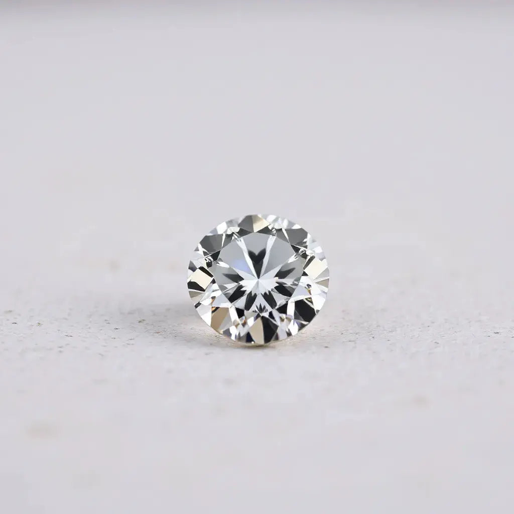 A sharply faceted diamond gem with bright reflections on a neutral background