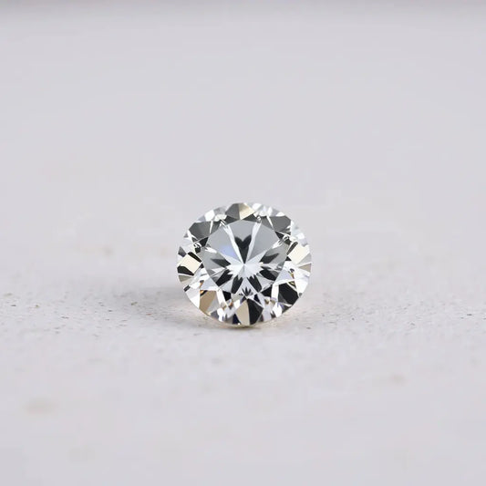A sharply faceted diamond gem with bright reflections on a neutral background