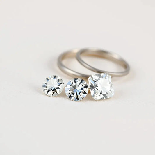 Round and cushion lab grown diamond gemstones with subtle sparkle on a neutral fabric backdrop
