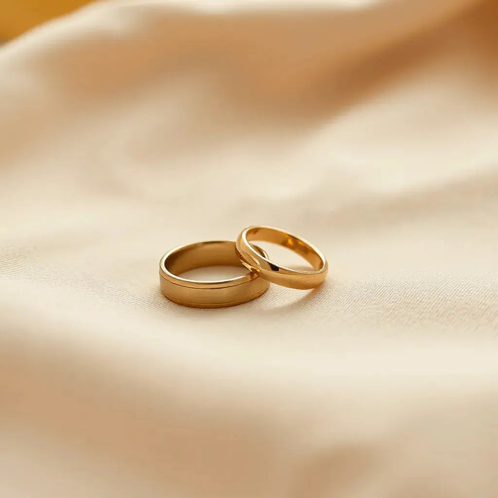 Two yellow gold wedding bands with polished shine resting on soft neutral fabric