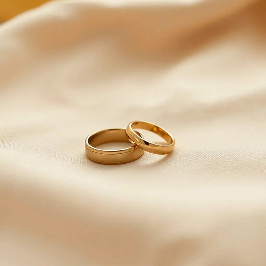 Two yellow gold wedding bands with polished shine resting on soft neutral fabric