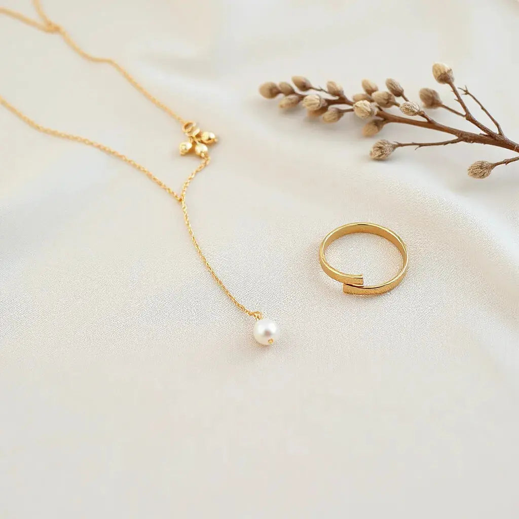 Gold necklace, earrings, bracelet and ring arranged on neutral fabric with soft lighting