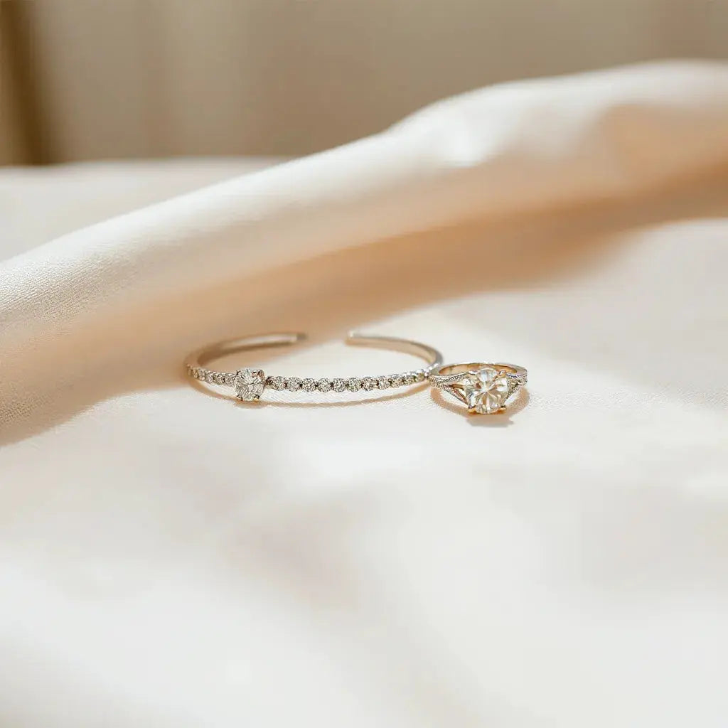 Delicate diamond stud earrings, necklace, bracelet and ring arranged on neutral fabric