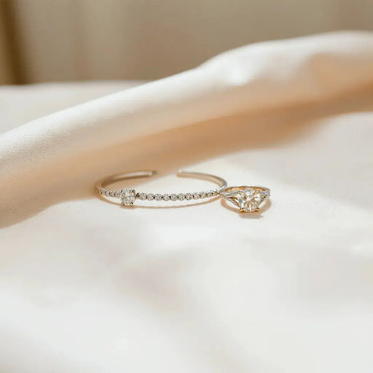 Delicate diamond stud earrings, necklace, bracelet and ring arranged on neutral fabric