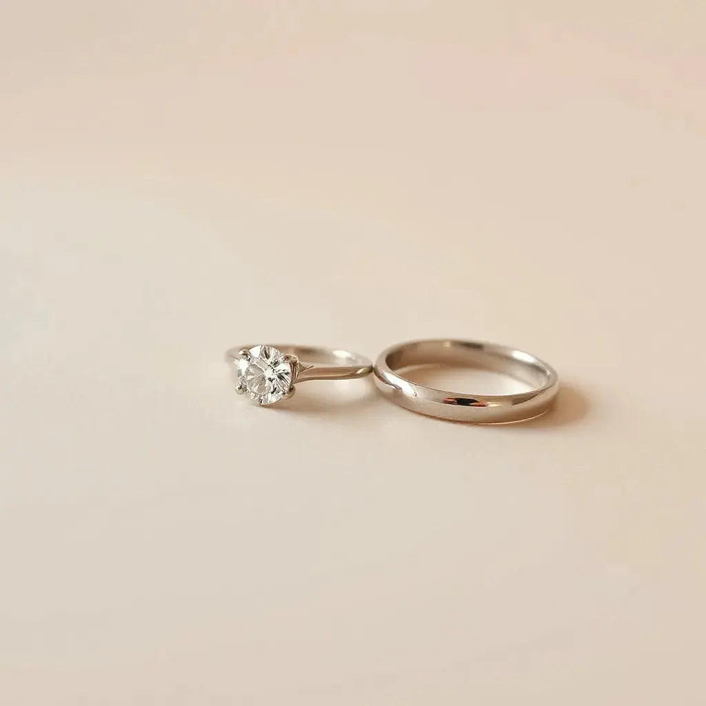 Minimalist modern engagement rings with a round center stone and sleek metal bands on a neutral background
