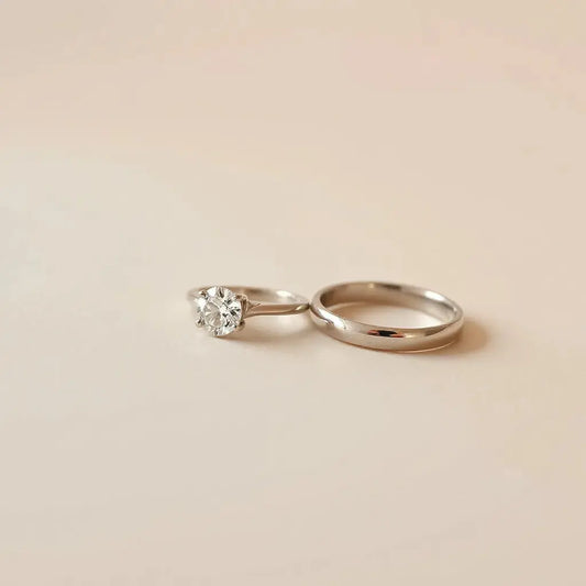Minimalist modern engagement rings with a round center stone and sleek metal bands on a neutral background