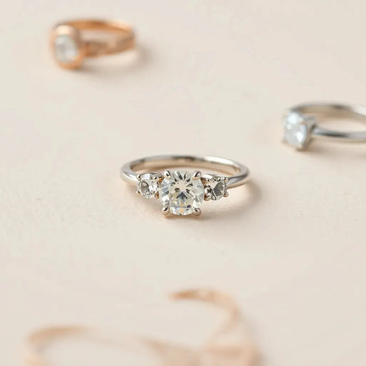 Trilogy engagement ring with three gemstones on a soft neutral background