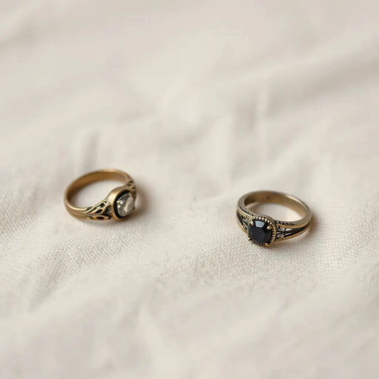 Three vintage style rings with filigree detail on neutral linen under warm soft light