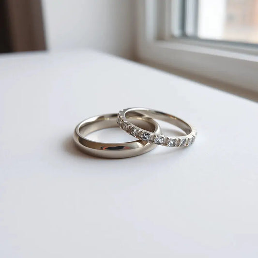 Two modern bridal rings with minimalist metal bands and subtle gemstone accents on a light background