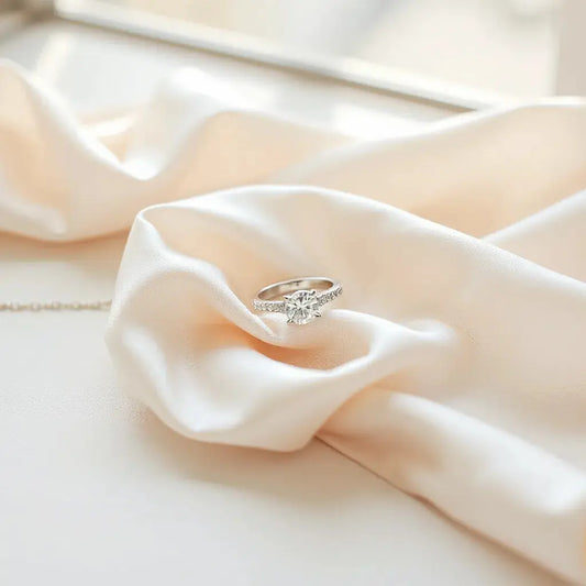 Delicate wedding ring, matching earrings, and a pendant necklace on white satin fabric