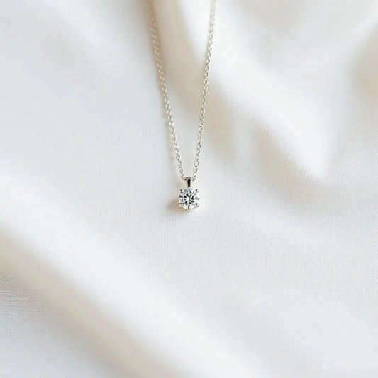 Diamond necklace with delicate round stones displayed on neutral fabric under soft studio lighting