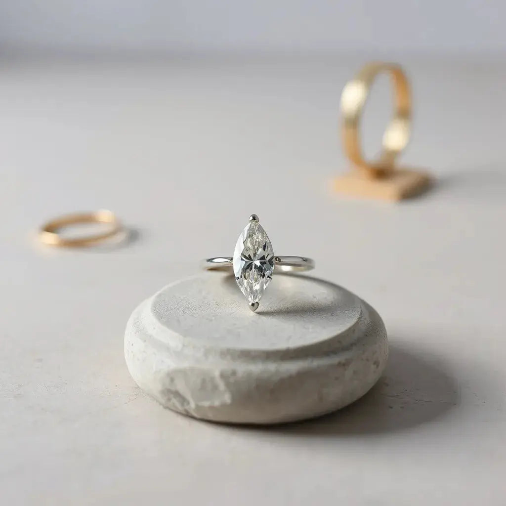 Marquise diamond ring with a sleek setting on a neutral surface, showing the stone’s elongated sparkle