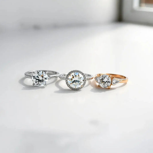 Three elegant diamond rings with sparkling stones on a neutral background