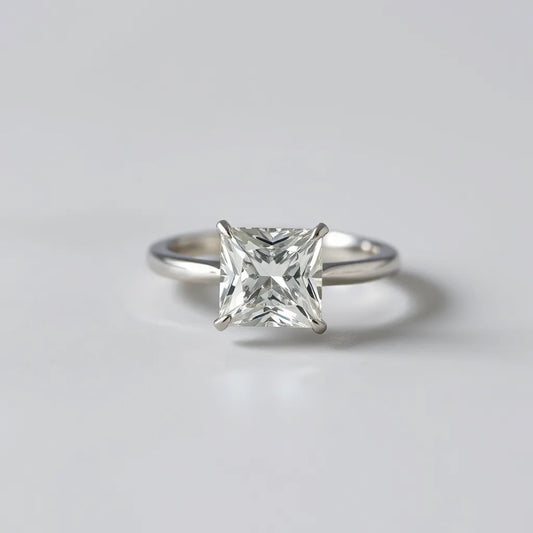 Princess cut diamond ring with square facets and a simple band on a light gray background