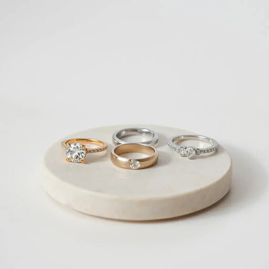 Assorted elegant luxury-style rings on a minimalist tray under soft natural light