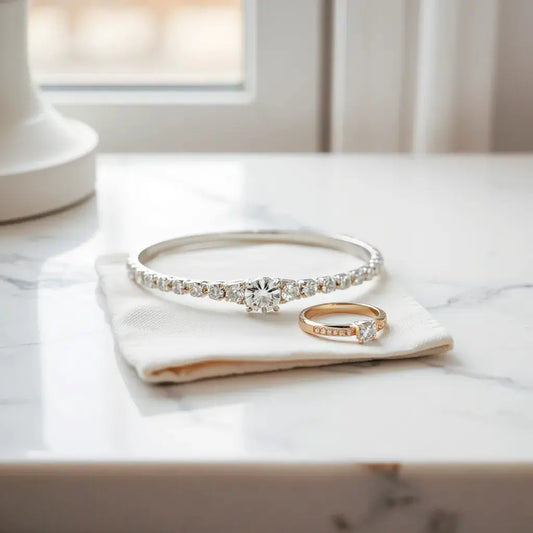 Handcrafted diamond ring and bracelet on white marble with a polishing cloth nearby