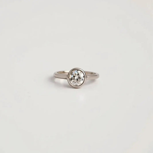 Oval bezel-set solitaire ring with an oval-cut center diamond on a clean neutral background