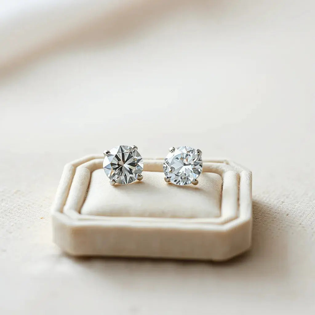 Two lab grown diamond studs with a small gem tray on a neutral background
