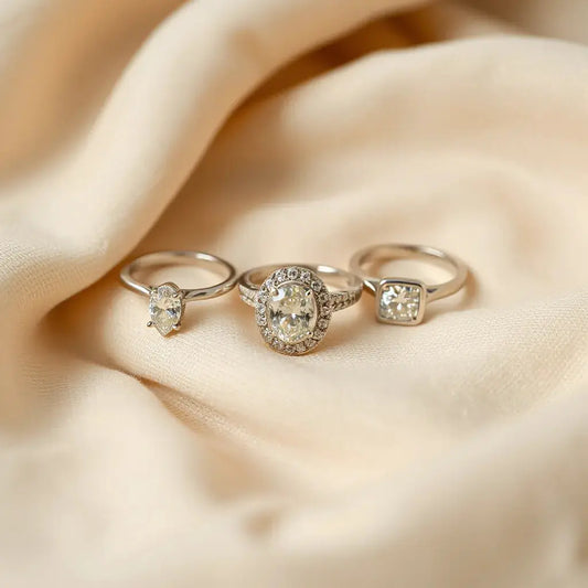 Assorted engagement rings on neutral fabric with sparkling diamond settings in a styled flat lay