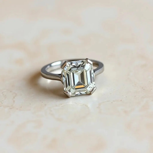 Emerald cut diamond engagement ring with a halo setting on a neutral background