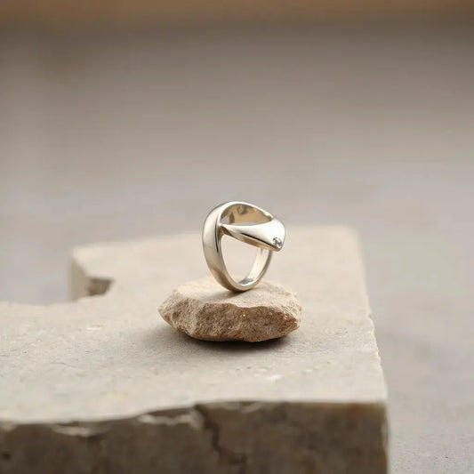 Modern sculptural ring with an architectural metal design on a neutral stone background