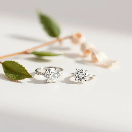 Two diamond solitaire rings with subtle sparkle on a light neutral background