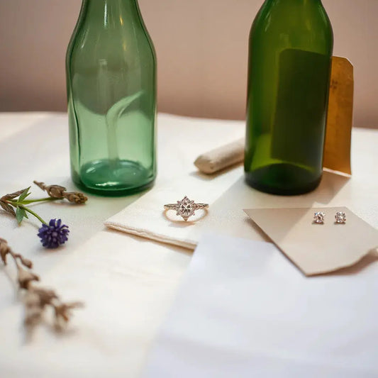 A diamond ring and studs on light linen with eco-inspired elements in soft natural light