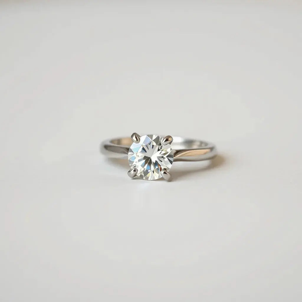 Four-prong solitaire diamond ring with prongs holding the center stone in soft studio light