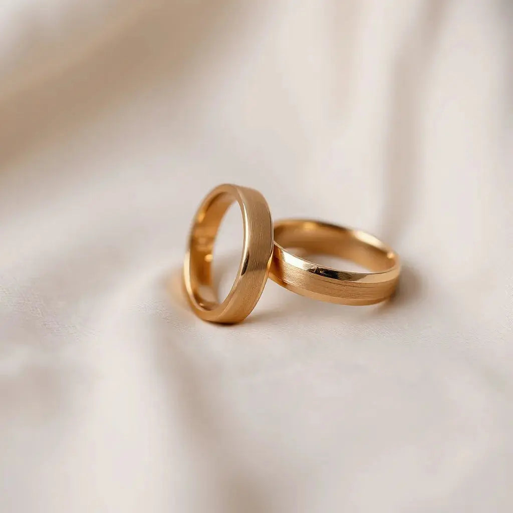 Two matching engraved wedding bands on a neutral fabric background with soft studio lighting