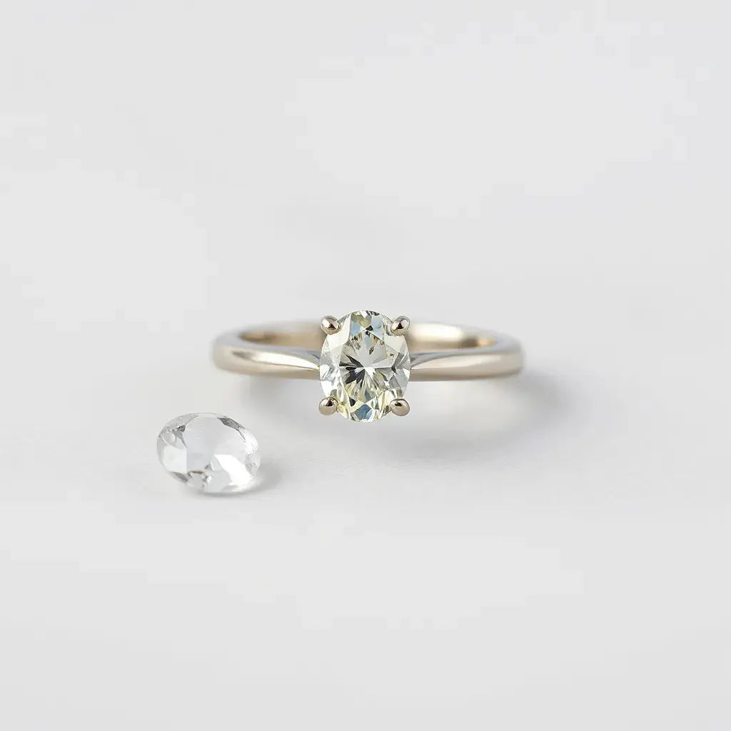 Oval-cut diamond ring in a solitaire setting on a clean light background with soft sparkle