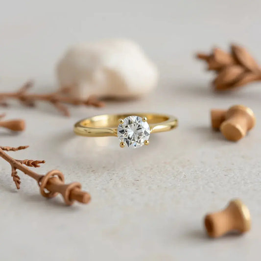 A 14k gold engagement ring with a round diamond centerpiece on a neutral background