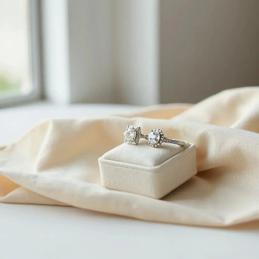 Two elegant engagement rings with diamond settings resting on neutral fabric in soft window light