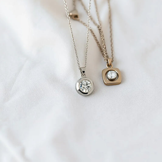Assorted diamond pendant necklaces with delicate chains on a neutral fabric background