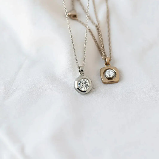 Assorted diamond pendant necklaces with delicate chains on a neutral fabric background
