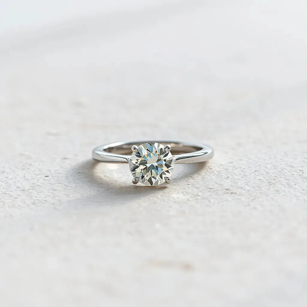 A solitaire diamond ring with a single round brilliant stone in a minimalist prong setting on a neutral background