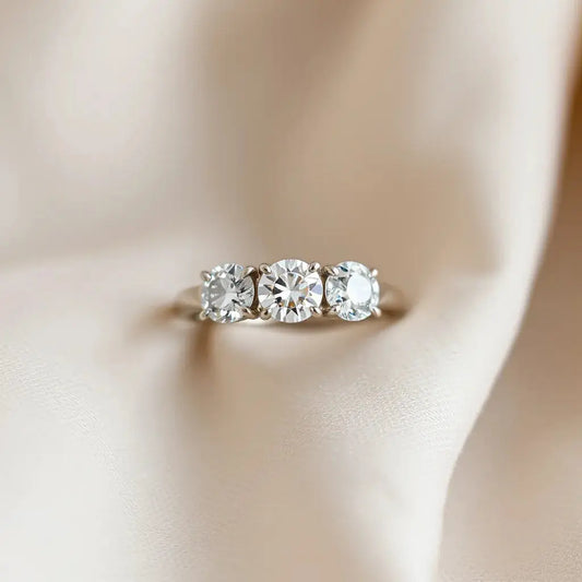 Trilogy diamond ring with three sparkling stones on a neutral fabric background