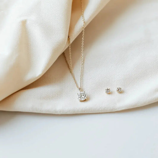 Delicate fine jewellery set with diamond pendant, tennis bracelet, and gemstone stud earrings on neutral fabric