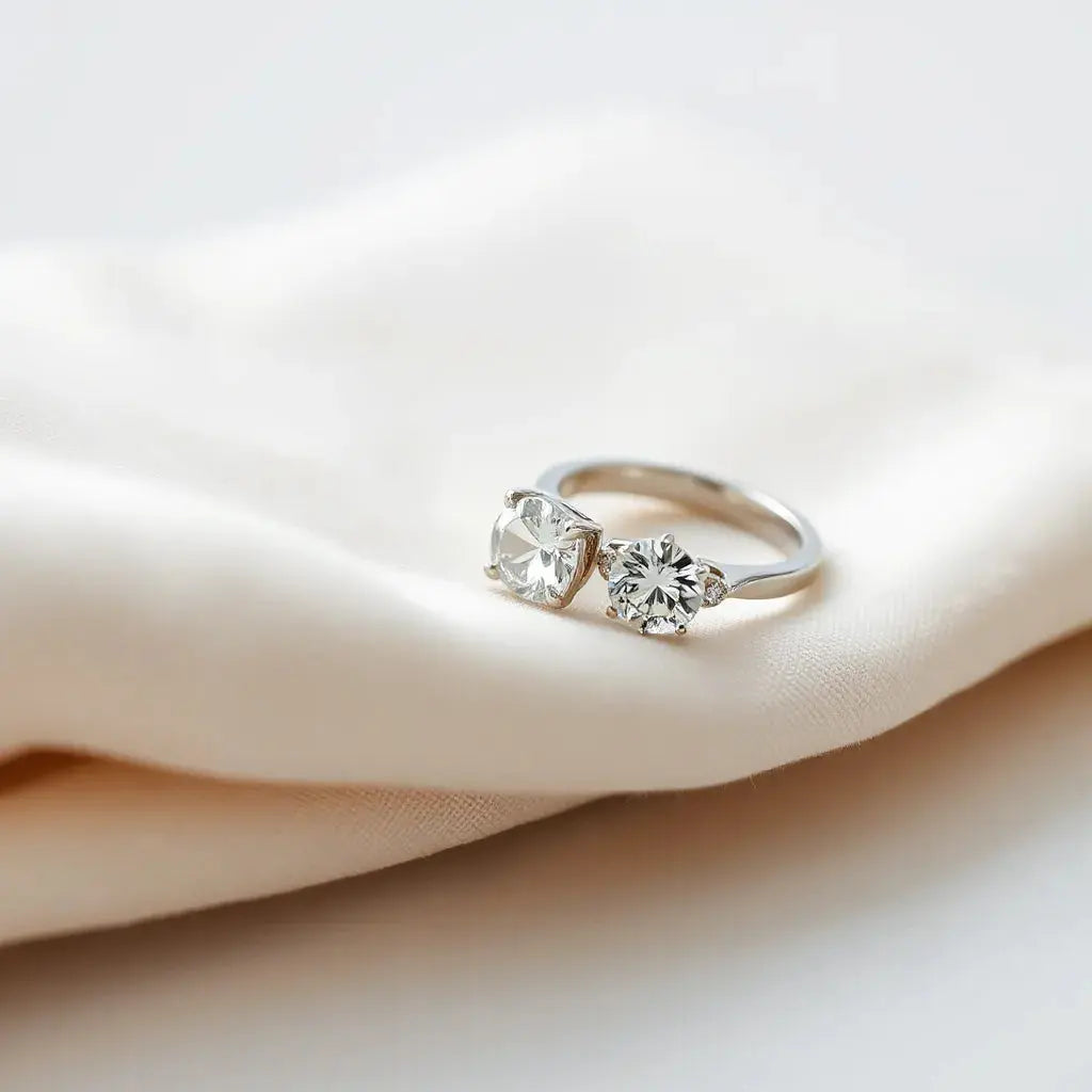 Two elegant lab-grown diamond rings with clear stones on a neutral fabric backdrop