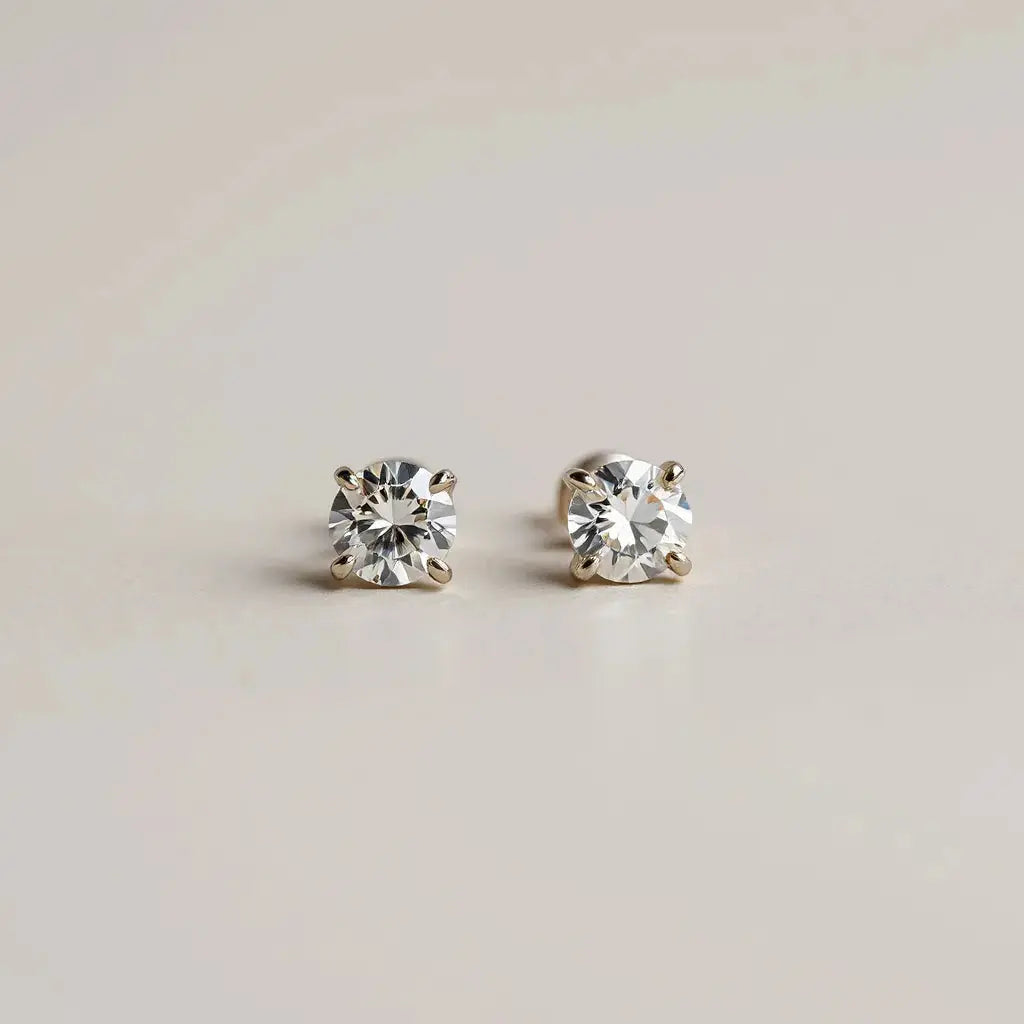 Pair of diamond stud earrings with visible sparkle on a clean neutral background