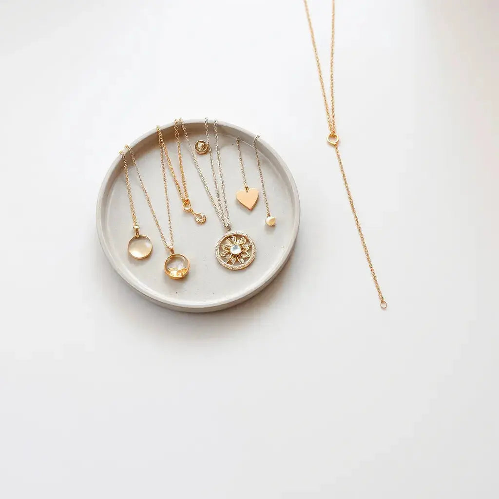 Assorted elegant pendants on short and long chains arranged on a neutral surface