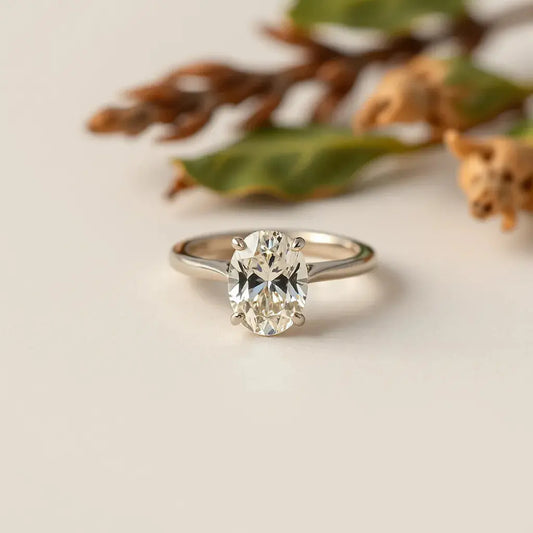 Oval diamond ring with visible prong setting and band texture on a neutral background