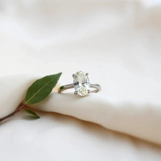 Moval lab-grown engagement ring with tapered oval gemstone on neutral fabric under soft window light