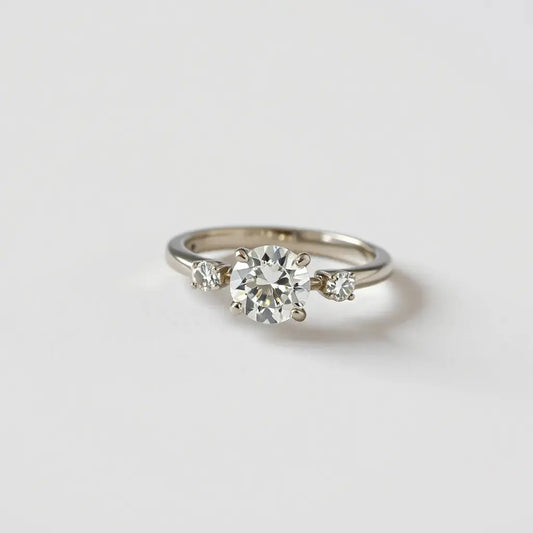 Diamond ring with side stones and a central gem, shown with soft studio lighting on a neutral background