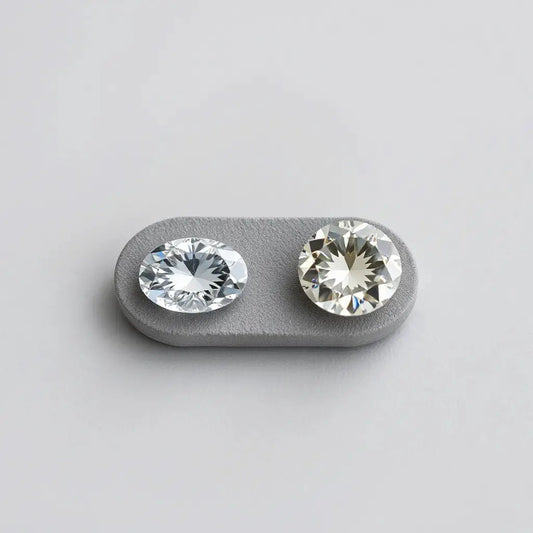 Two loose diamonds side by side showing oval and moval cut shapes on a neutral background