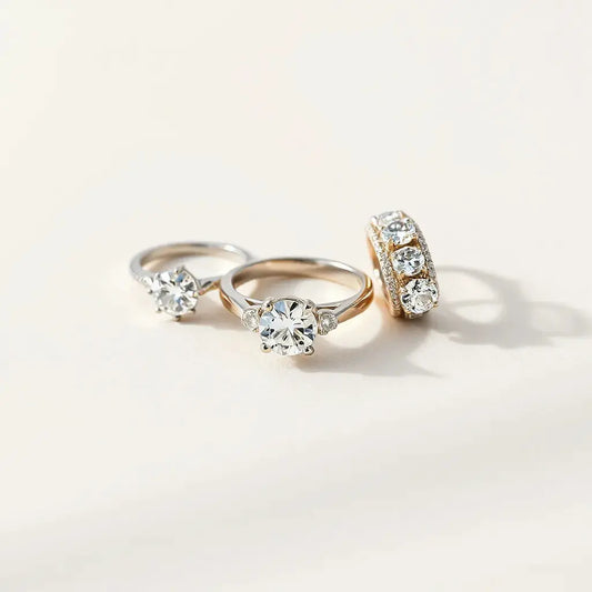 Three elegant moissanite rings with sparkling stones in solitaire, halo, and three-stone styles