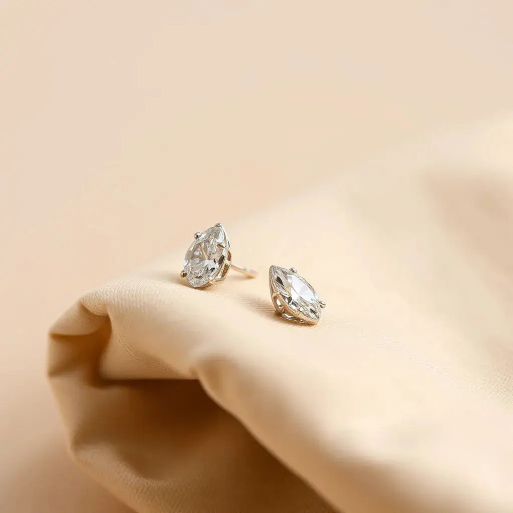 Pair of elegant diamond earrings with subtle sparkle on neutral fabric under soft natural light