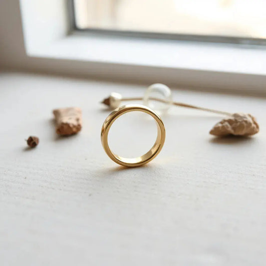 A polished 10K yellow gold ring on a neutral background with soft natural lighting