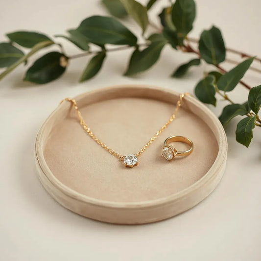 Gold necklace and diamond ring on a velvet tray with soft warm lighting and subtle gemstone sparkle